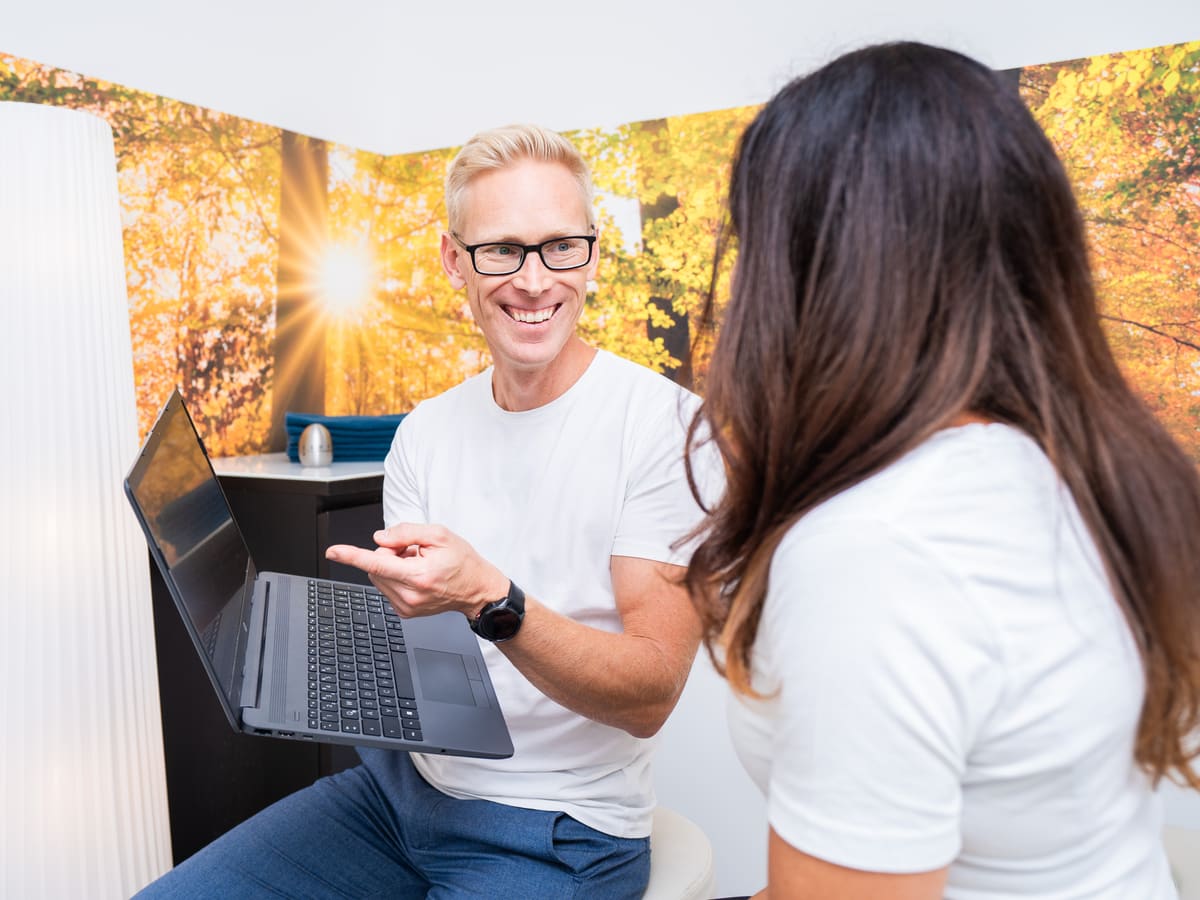 Therapeut bespricht mit einer Patientin die Analyse am Laptop