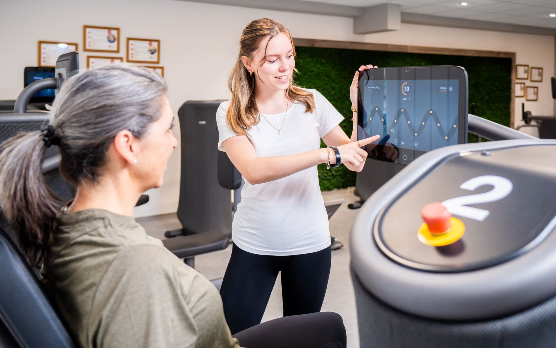 Therapeutin erklärt einer Patientin das Trainingsgerät