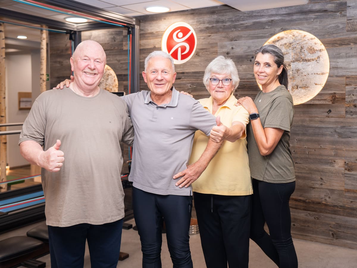 Zufriedene Patient:innen mit Therapeutin im Trainingsbereich