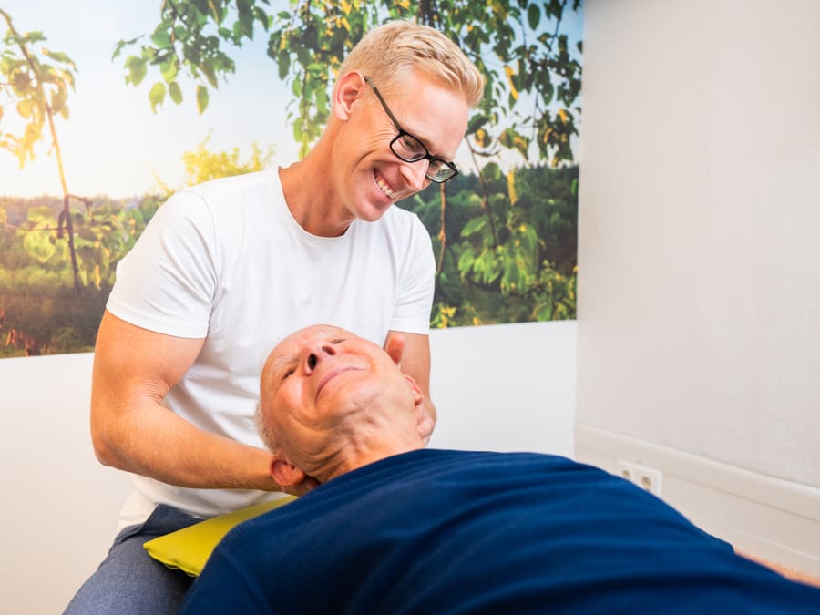 Therapeut behandelt einen Patienten auf der Therapieliege